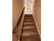 Carpeted staircase features a stained banister and beige carpeted steps at 1935 Manor Pointe Dr, Cumming, GA 30041