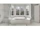 Bright bathroom with a large soaking tub, white marble surround, and large windows with bright white shutters at 3980 Saint Elisabeth Sq, Duluth, GA 30096