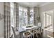 Bright dining room features large windows with curtains, hardwood floors and elegant chandelier lighting at 3980 Saint Elisabeth Sq, Duluth, GA 30096