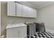 Bright laundry room with checkerboard floors, upper and lower white cabinets, sink, washer and dryer at 3980 Saint Elisabeth Sq, Duluth, GA 30096