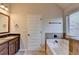 Bathroom with marble countertops, cabinets, soaking tub, toilet, and window that provides natural light at 1465 Forest Brook Trl, Cumming, GA 30041
