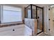 Bright bathroom features a soaking tub and tiled shower with glass door, next to the door at 1465 Forest Brook Trl, Cumming, GA 30041