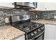 Close up of a stainless steel gas range stove top with granite countertops and black tiled backsplash at 2599 Church Nw St, Atlanta, GA 30318