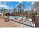 An inviting backyard offers a view of the pool with a wooden deck, trees and blue sky at 2762 Whitehurst Ne Dr, Marietta, GA 30062