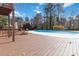 Large blue pool with a backyard wooden deck surrounded by green trees on a sunny day at 2762 Whitehurst Ne Dr, Marietta, GA 30062