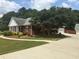 View of the home with a red brick exterior, lush green lawn, and a long driveway at 3220 Indian Shoals Rd, Dacula, GA 30019