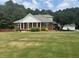 Charming brick home with a manicured lawn, columns, and a well-maintained landscape at 3220 Indian Shoals Rd, Dacula, GA 30019