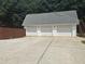 Three car garage with white doors, gray roof and driveway parking with exterior staircase on the side at 3220 Indian Shoals Rd, Dacula, GA 30019