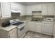 Well-lit kitchen featuring white cabinets, countertops and appliances offers a clean and functional cooking space at 3220 Indian Shoals Rd, Dacula, GA 30019