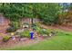 A beautiful backyard garden featuring a variety of plants, flowers, decorations, and a white garden bench at 3460 Trow Creek Ln, Cumming, GA 30040