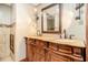 Bathroom with a double vanity featuring wooden cabinetry, marble countertop, decorative mirror, and lighting at 6069 Shallow Wood Ln, Douglasville, GA 30135