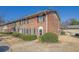 Two-story brick townhome featuring manicured shrubs, dark shutters, and a concrete walkway at 413 Northdale Ct, Lawrenceville, GA 30046