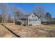 Backyard of the house showcasing the exterior, screened porch, and a large grassy area with mature trees at 459 Rabbit Run, Mcdonough, GA 30252