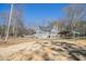 View of a quaint home with a large yard, shed, and metal carport under a clear blue sky at 459 Rabbit Run, Mcdonough, GA 30252