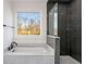 A luxurious bathroom features a soaking tub next to a glass shower, tiled with dark gray subway tiles at 244 Locust Ne St # B, Atlanta, GA 30317