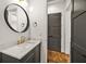 Powder room featuring marble countertop, modern fixtures, decorative mirror, and gray cabinets at 244 Locust Ne St # B, Atlanta, GA 30317