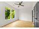 Bright bedroom featuring a ceiling fan, hardwood floors and a large window view to green trees at 244 Locust Ne St # B, Atlanta, GA 30317