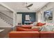 Modern living room with an orange sectional couch and sleek staircase design at 1218 Crestwood Se Dr, Atlanta, GA 30316