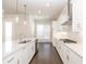 Modern kitchen featuring white cabinetry, granite countertops, stainless steel appliances and dark hardwood floors at 167 Basil Street, Cumming, GA 30040