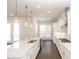 Bright kitchen features white cabinets, granite countertops, stainless steel appliances and modern pendant lighting at 167 Basil Street, Cumming, GA 30040