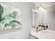 Stylish half-bathroom featuring a white sink, framed tropical artwork, modern light fixtures, and elegant, neutral tones at 3721 Stonewall Se Cir, Atlanta, GA 30339