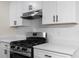 Close-up of a kitchen with stainless steel gas range, white counters, and modern white cabinets at 2966 Knollberry Ln, Decatur, GA 30034