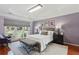 Charming bedroom featuring hardwood floors, a large window, tray ceiling, and bench at the end of the bed at 1030 Whistling Swan Pl, Marietta, GA 30066