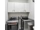 Laundry room featuring two front loading stainless steel washer and dryer units and white storage cabinets at 1030 Whistling Swan Pl, Marietta, GA 30066