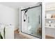 A bathroom with a modern glass shower featuring black hardware, white tile and flooring, with a marble vanity at 545 Woodale Se Dr, Smyrna, GA 30080