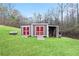 Shed in backyard with double red doors and open side area for wood storage at 209 Sweetwater Trl, Villa Rica, GA 30180