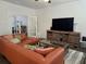 Inviting living room with an orange sectional sofa, a large TV, and French doors leading to a bright sunroom at 1200 Bar Harbor Pl, Lawrenceville, GA 30044
