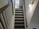Staircase with dark wood treads, white risers and banisters, and a modern wall sconce for added illumination at 1200 Bar Harbor Pl, Lawrenceville, GA 30044