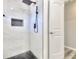 This modern shower features sleek white tiles, a rainfall showerhead, and a convenient built-in niche for storage at 406 Jordan Dr, Tucker, GA 30084