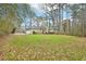 Back of a beige home with a two-car garage surrounded by a large lawn and tall trees at 105 Spring Forest Way, Sharpsburg, GA 30277