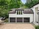 An oversized three-car garage with black doors, featuring a light-colored exterior and concrete driveway at 4000 Wieuca Ne Rd, Atlanta, GA 30342