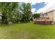 Large grassy backyard with mature trees, and a large wooden deck at 5678 Fern Creek Sw Dr, Lilburn, GA 30047