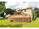 View of the backyard with wooden deck, manicured lawn, and mature trees at 5678 Fern Creek Sw Dr, Lilburn, GA 30047