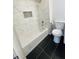 Modern bathroom featuring a tub with stylish marble-patterned tiles and black floors at 5678 Fern Creek Sw Dr, Lilburn, GA 30047