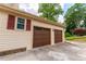 Attached two-car garage with wooden doors and exterior lighting, adding curb appeal to the home at 5678 Fern Creek Sw Dr, Lilburn, GA 30047