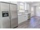 Renovated kitchen with stainless steel refrigerator, updated cabinets, countertops and new gray vinyl plank flooring at 5678 Fern Creek Sw Dr, Lilburn, GA 30047