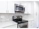 Close up of oven and microwave shows stainless steel appliances, countertops, and cabinets at 5678 Fern Creek Sw Dr, Lilburn, GA 30047