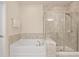 Bright bathroom featuring a tub and glass enclosed shower with custom tile surround at 2289 Emerald Sky Dr, Smyrna, GA 30080