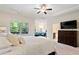 Bright main bedroom featuring a tray ceiling, ceiling fan, sitting area, and en suite bathroom at 2289 Emerald Sky Dr, Smyrna, GA 30080