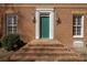 Close-up of a brick home's entry, with a green front door, brick steps, and sconces at 270 Grapevine Run, Sandy Springs, GA 30350