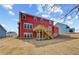 View of a vibrant red home's backyard, featuring a wooden deck and staircase, surrounded by a naturally landscaped area at 4039 Andover Cir, Mcdonough, GA 30252