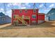 Red two-story home with a wooden deck and staircase leading to a well-maintained yard at 4039 Andover Cir, Mcdonough, GA 30252