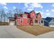 Stunning two-story red home featuring a two-car garage and classic front porch at 4039 Andover Cir, Mcdonough, GA 30252