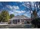 View of the backyard featuring a red brick house with a screened-in porch and mature trees at 520 Camp Perrin Rd, Lawrenceville, GA 30043