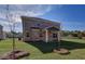 Brick home backyard with covered porch, lush green lawn, and clear blue sky at 249 Chiswick Loop, Stockbridge, GA 30281