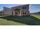 A spacious, grassy backyard with a covered porch and the brick facade of the house at 249 Chiswick Loop, Stockbridge, GA 30281